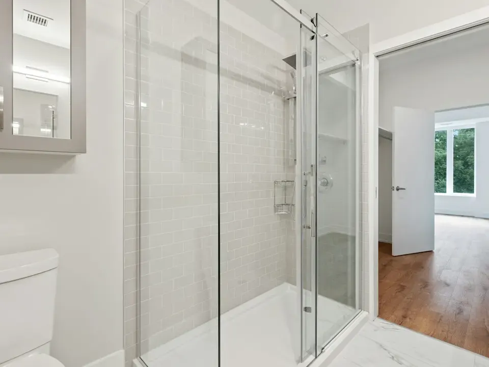 Ebenerdige Dusche mit Glasschiebetür in einem hellen Bad
