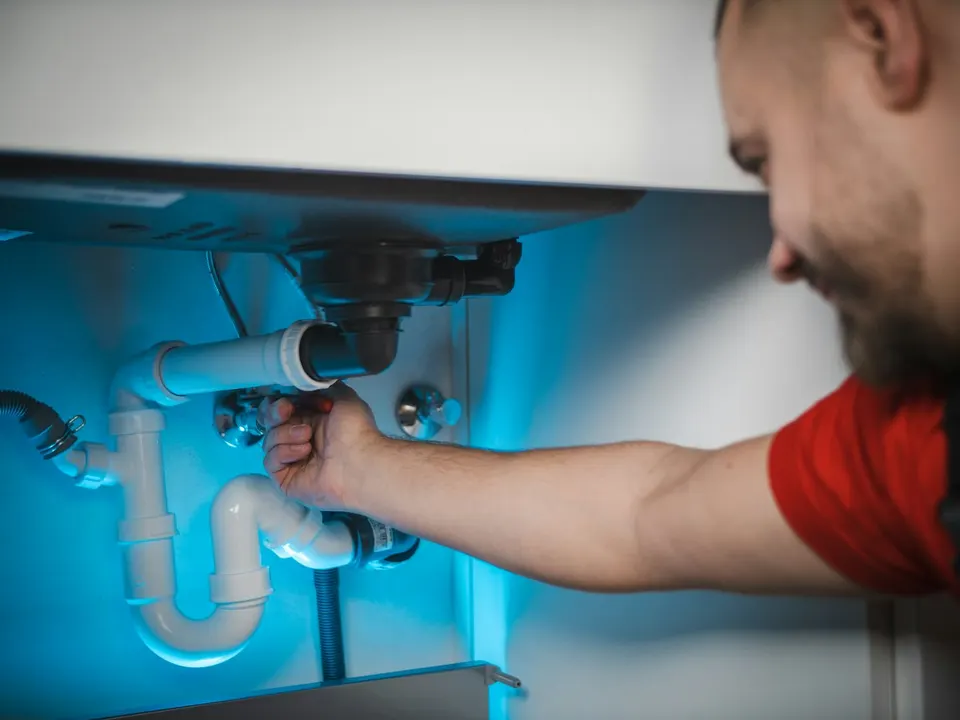 Installateur montiert den Siphon unter einem Waschtisch